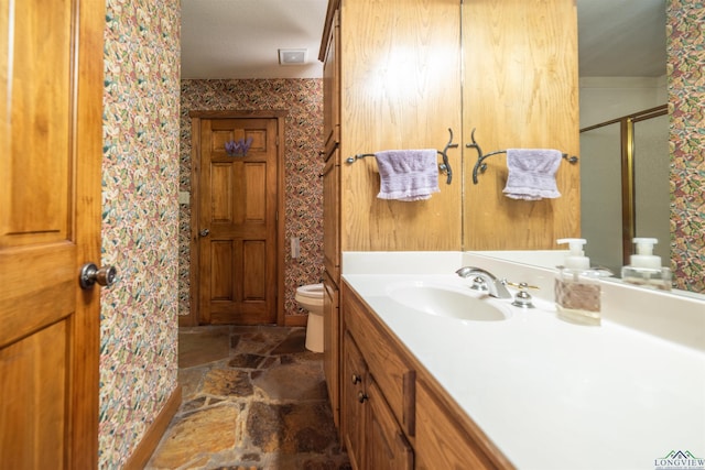 bathroom with a shower with door, vanity, and toilet