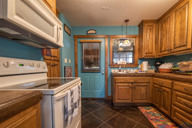 kitchen featuring white appliances, dark tile patterned floors, exhaust hood, sink, and decorative light fixtures