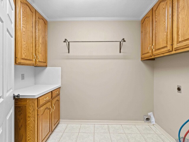 laundry room featuring cabinet space, light tile patterned floors, crown molding, electric dryer hookup, and baseboards