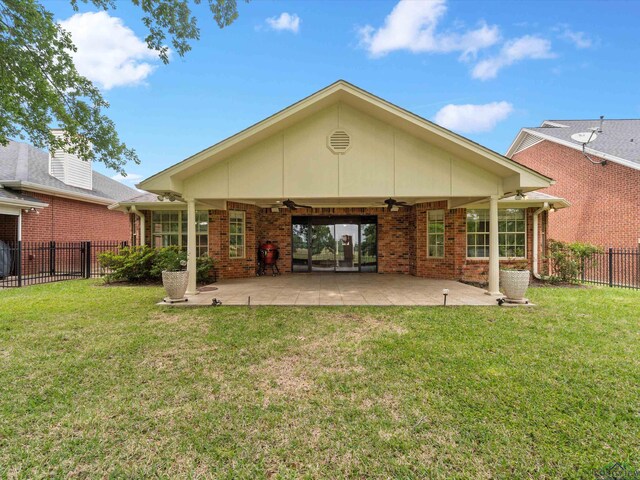 back of property with a lawn, a ceiling fan, fence, and brick siding
