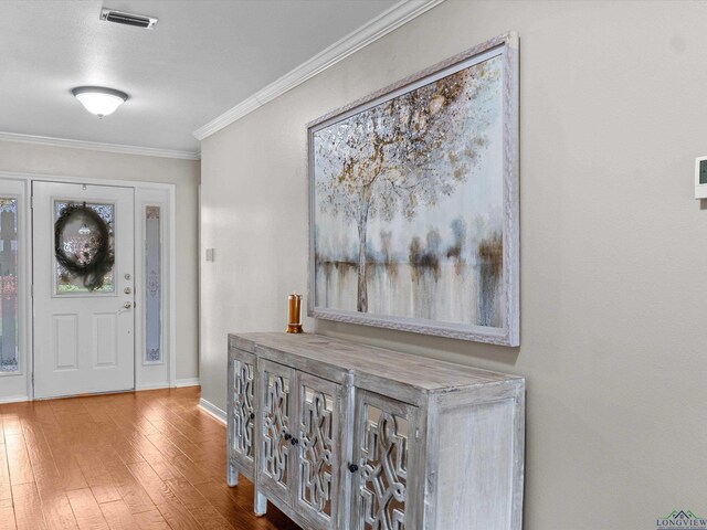 foyer entrance with wood finished floors, visible vents, ornamental molding, and baseboards