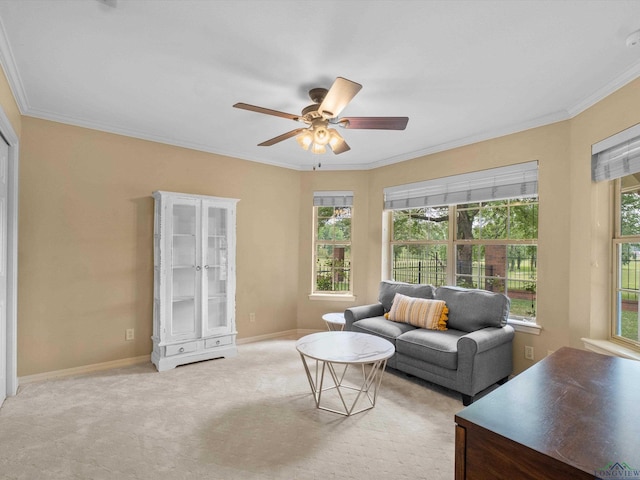 living area with ornamental molding, a ceiling fan, light colored carpet, and baseboards