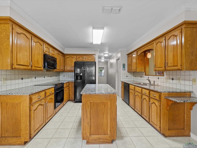 kitchen featuring black appliances, visible vents, a kitchen island, and brown cabinetry