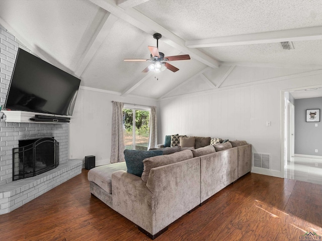 living room with a textured ceiling, ceiling fan, lofted ceiling with beams, a fireplace, and dark hardwood / wood-style floors