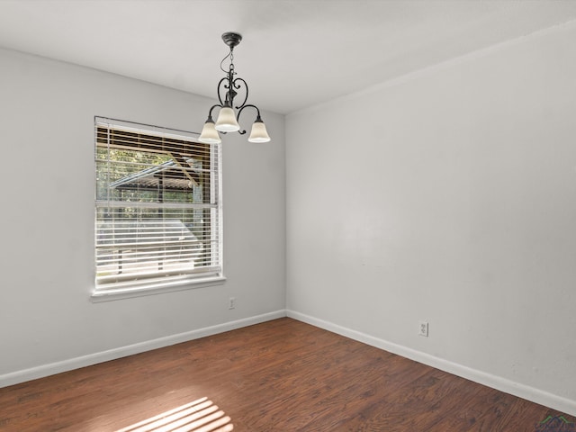 unfurnished room with hardwood / wood-style floors and an inviting chandelier