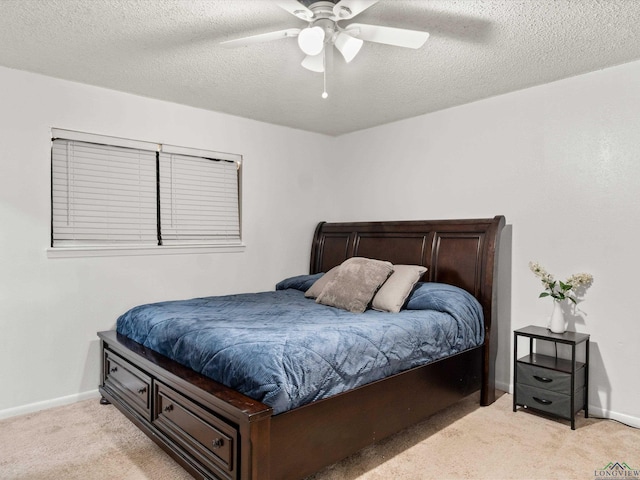 bedroom with ceiling fan, light colored carpet, and a textured ceiling