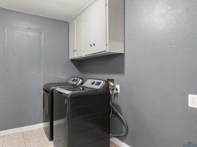 washroom featuring washer and dryer, cabinets, and light tile patterned floors