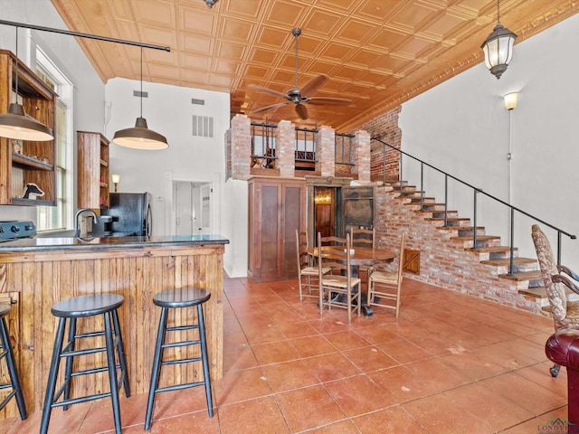 kitchen with pendant lighting, ceiling fan, black fridge, and brick wall