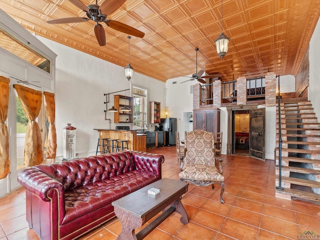 tiled living room featuring a towering ceiling, ceiling fan, and sink