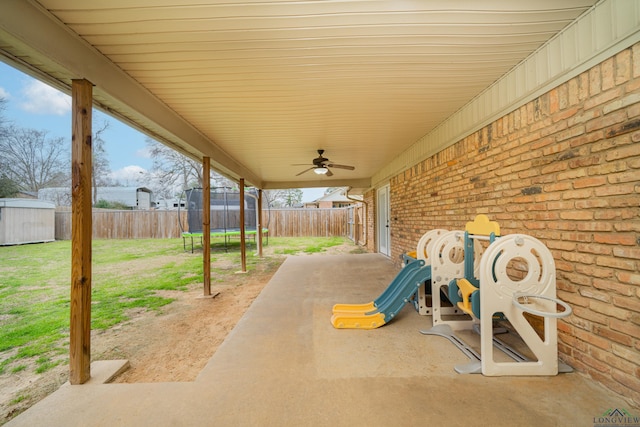 view of patio / terrace featuring a fenced backyard, a trampoline, a playground, and a shed