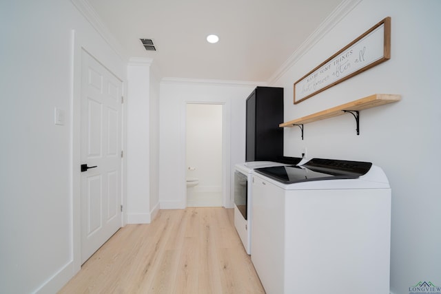 clothes washing area featuring visible vents, ornamental molding, light wood-style floors, washer and dryer, and laundry area