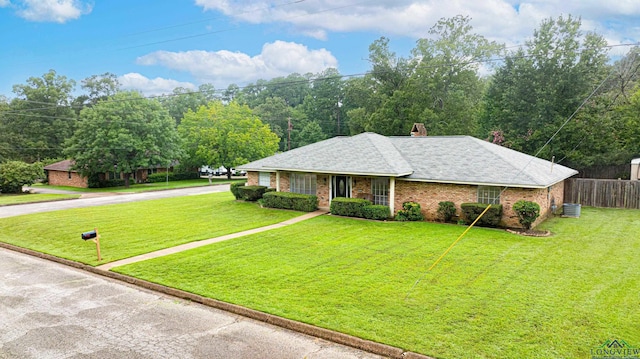 ranch-style house featuring brick siding, fence, and a front yard