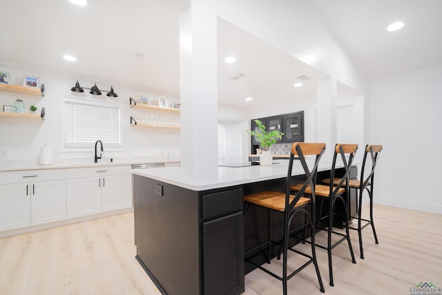 kitchen with open shelves, a kitchen island, light countertops, and white cabinets