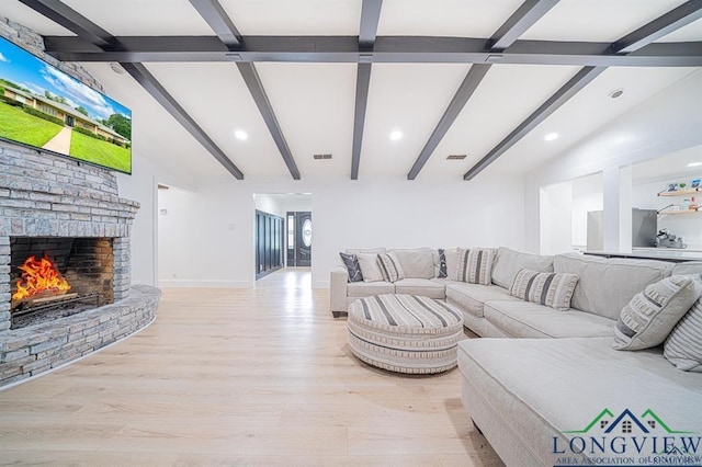 living room with light wood-type flooring, a brick fireplace, visible vents, and vaulted ceiling with beams