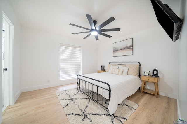 bedroom with ceiling fan, light wood-style flooring, and baseboards