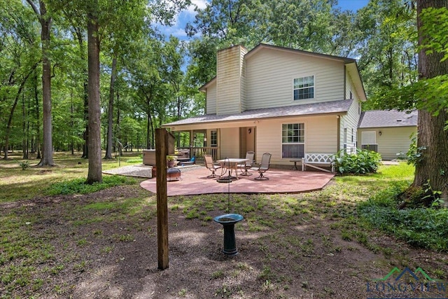 rear view of property with a chimney and a patio area