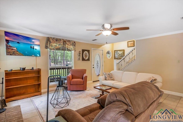 living room with light tile patterned flooring, a ceiling fan, crown molding, baseboards, and stairs