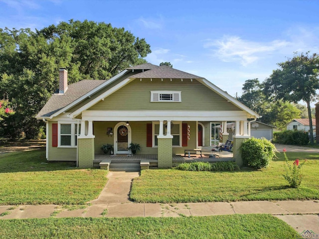 view of front of home with a chimney, a porch, and a front lawn