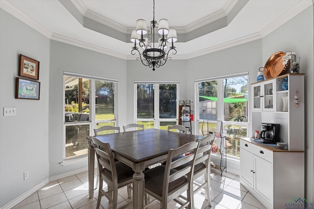 tiled dining space featuring a notable chandelier, a raised ceiling, crown molding, and a wealth of natural light