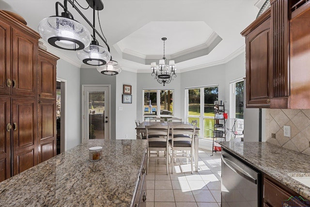 kitchen featuring decorative backsplash, light stone countertops, a tray ceiling, dishwasher, and hanging light fixtures