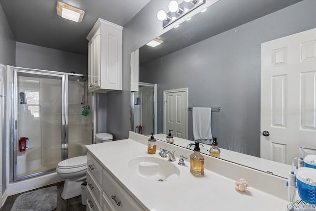 bathroom featuring vanity, hardwood / wood-style flooring, toilet, and a shower with door