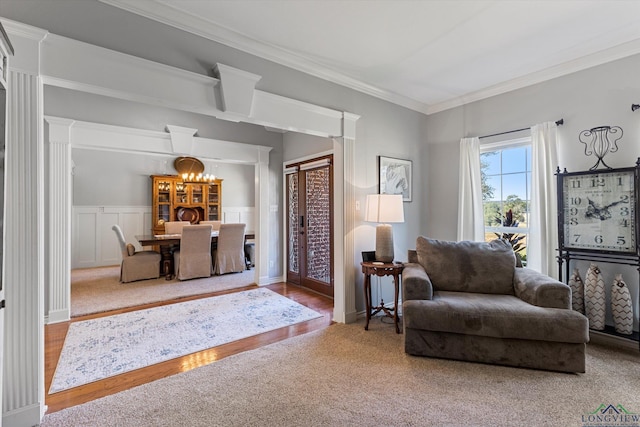 sitting room with ornate columns, crown molding, and a notable chandelier