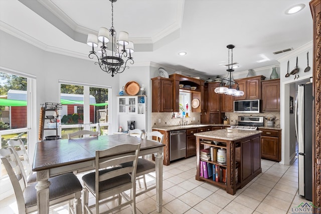 kitchen with hanging light fixtures, decorative backsplash, a tray ceiling, a kitchen island, and stainless steel appliances