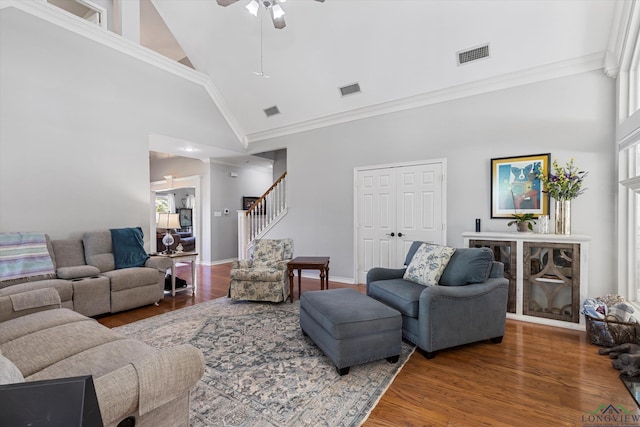 living room with high vaulted ceiling, ceiling fan, ornamental molding, a fireplace, and wood-type flooring