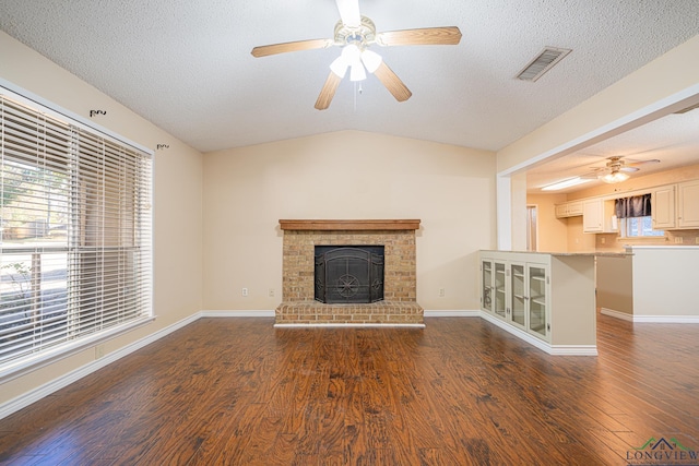 unfurnished living room featuring a fireplace, dark hardwood / wood-style flooring, a textured ceiling, and ceiling fan