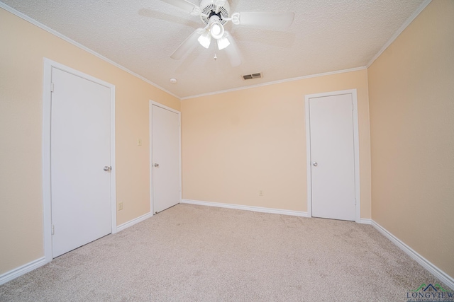 unfurnished bedroom featuring a textured ceiling, light colored carpet, ceiling fan, and ornamental molding