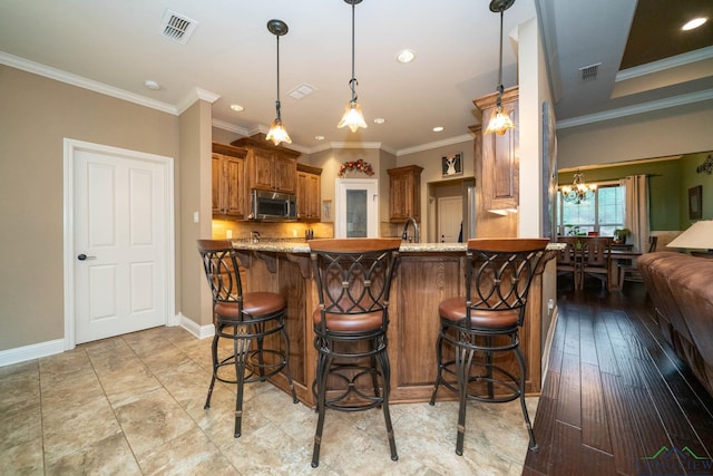 2106 Katie Lee Ln, Longview, TX 75601 - kitchen with stainless steel microwave, brown cabinets, a chandelier, a kitchen breakfast bar, and a peninsula