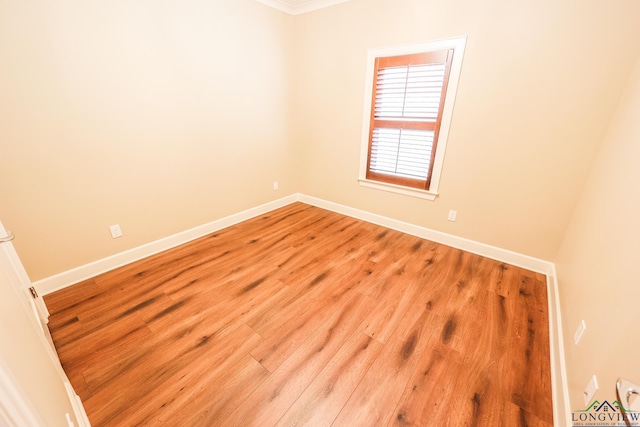 spare room featuring ornamental molding and light wood-type flooring