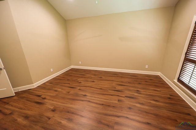 unfurnished room featuring dark hardwood / wood-style flooring and vaulted ceiling