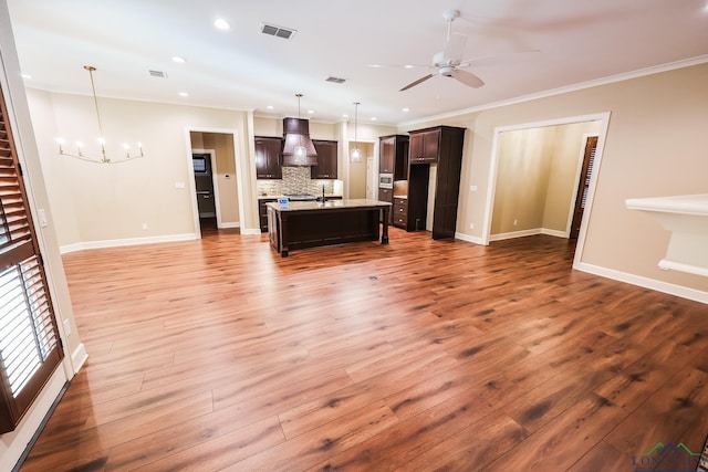 kitchen with backsplash, decorative light fixtures, premium range hood, and hardwood / wood-style floors