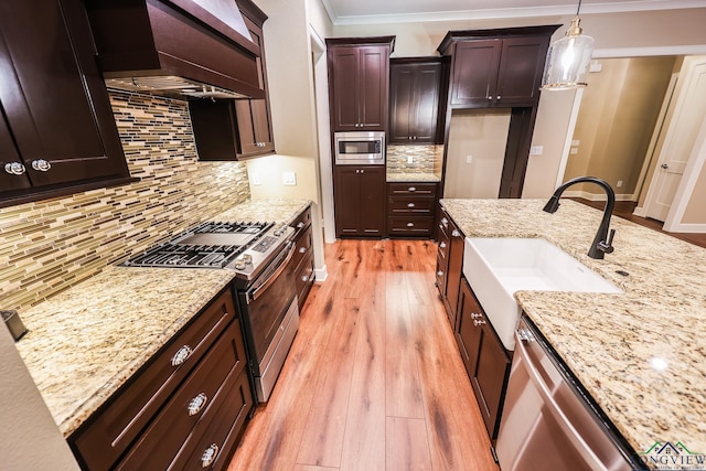 kitchen featuring premium range hood, sink, decorative backsplash, decorative light fixtures, and stainless steel appliances