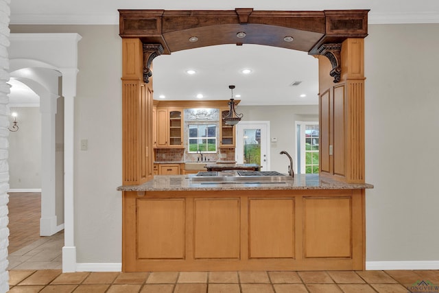 kitchen featuring stainless steel gas stovetop, sink, ornate columns, ornamental molding, and tasteful backsplash