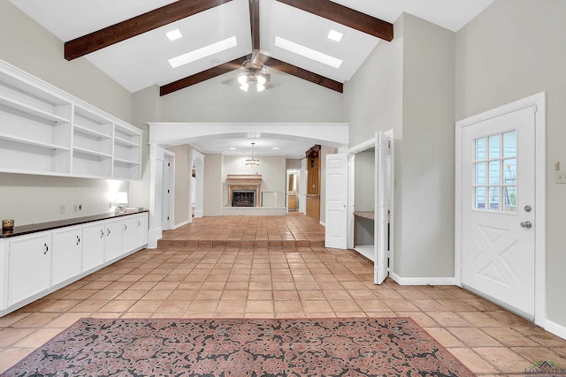 kitchen featuring high vaulted ceiling, white cabinets, a brick fireplace, ceiling fan, and beam ceiling