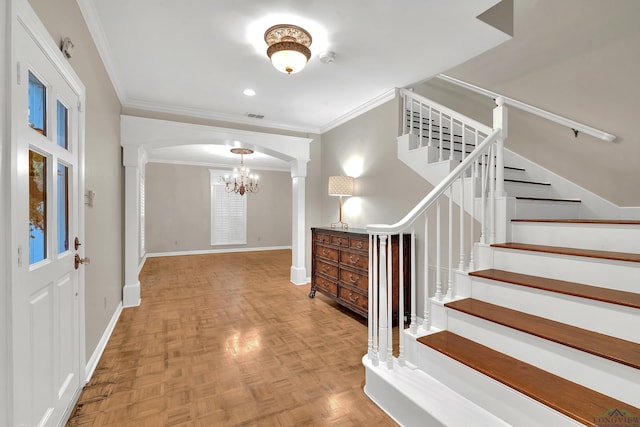 entrance foyer with a chandelier, light parquet flooring, decorative columns, and ornamental molding