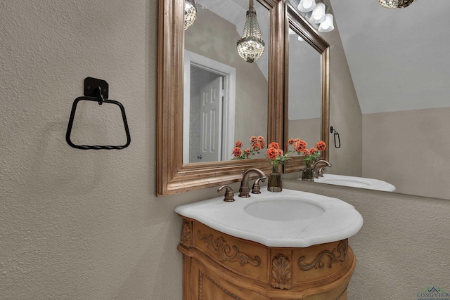 bathroom featuring vanity, an inviting chandelier, and vaulted ceiling