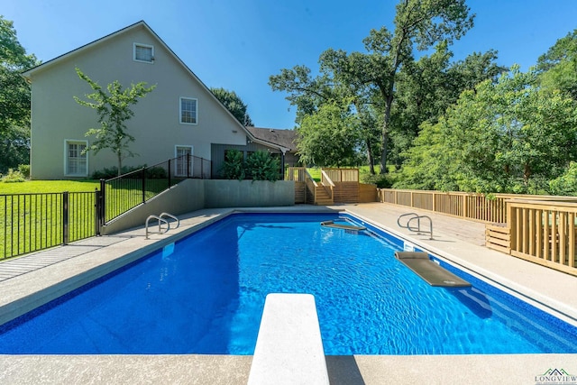 view of swimming pool featuring a yard, a diving board, and a wooden deck