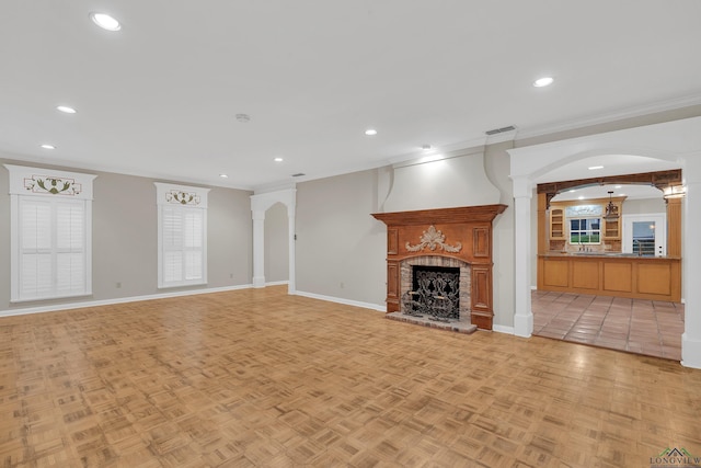 unfurnished living room with a fireplace, light parquet floors, and crown molding