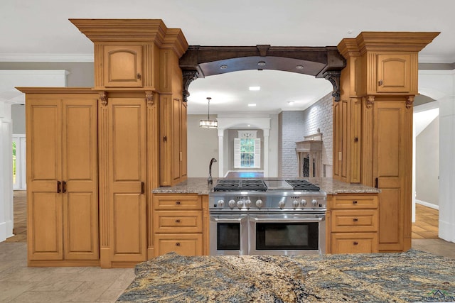 kitchen with dark stone countertops, range with two ovens, and ornamental molding