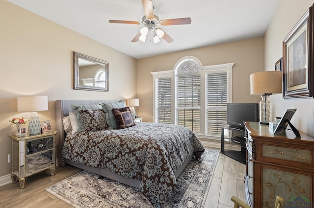 bedroom featuring ceiling fan, baseboards, and light wood-style flooring