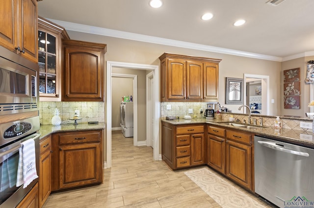 kitchen featuring a sink, stainless steel appliances, washer / dryer, and ornamental molding