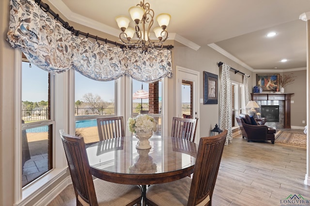 dining area featuring baseboards, light wood-style floors, an inviting chandelier, and ornamental molding