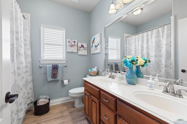 bathroom featuring double vanity, toilet, wood finished floors, and a sink