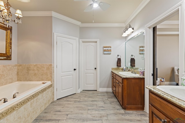 full bath with crown molding, a garden tub, two vanities, ceiling fan with notable chandelier, and a sink