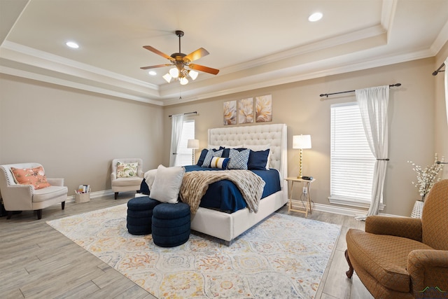 bedroom featuring a tray ceiling, baseboards, wood finished floors, and ornamental molding