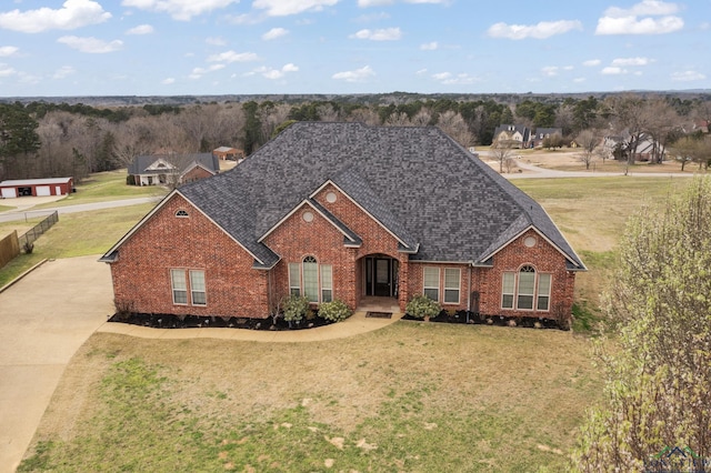 traditional-style house with a front lawn, brick siding, driveway, and roof with shingles