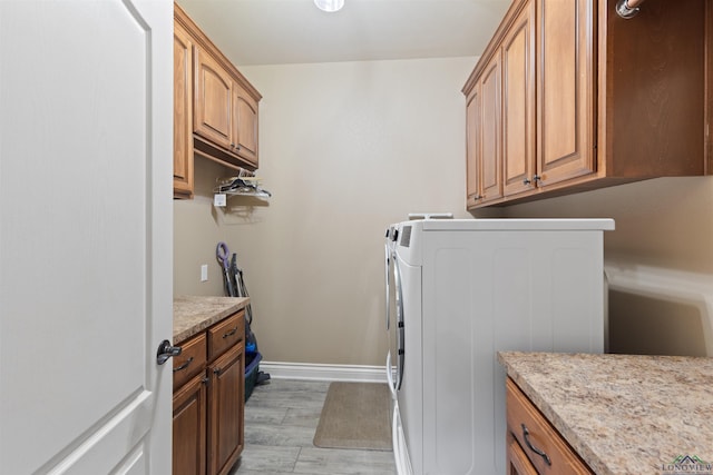 washroom with cabinet space, light wood-style floors, baseboards, and separate washer and dryer